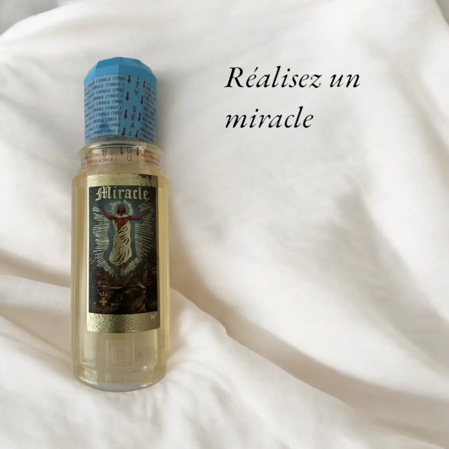 Une Bouteille du parfum Miracle posée sur un drap avec le slogan: Réalisez un miracle affiché à côté