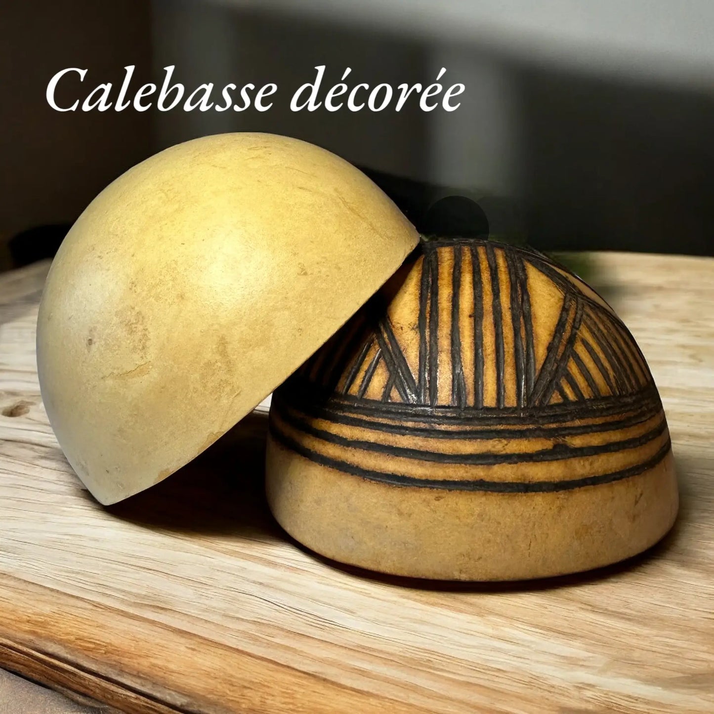 Une demi calebasse posée sur une demi calebasse décorée