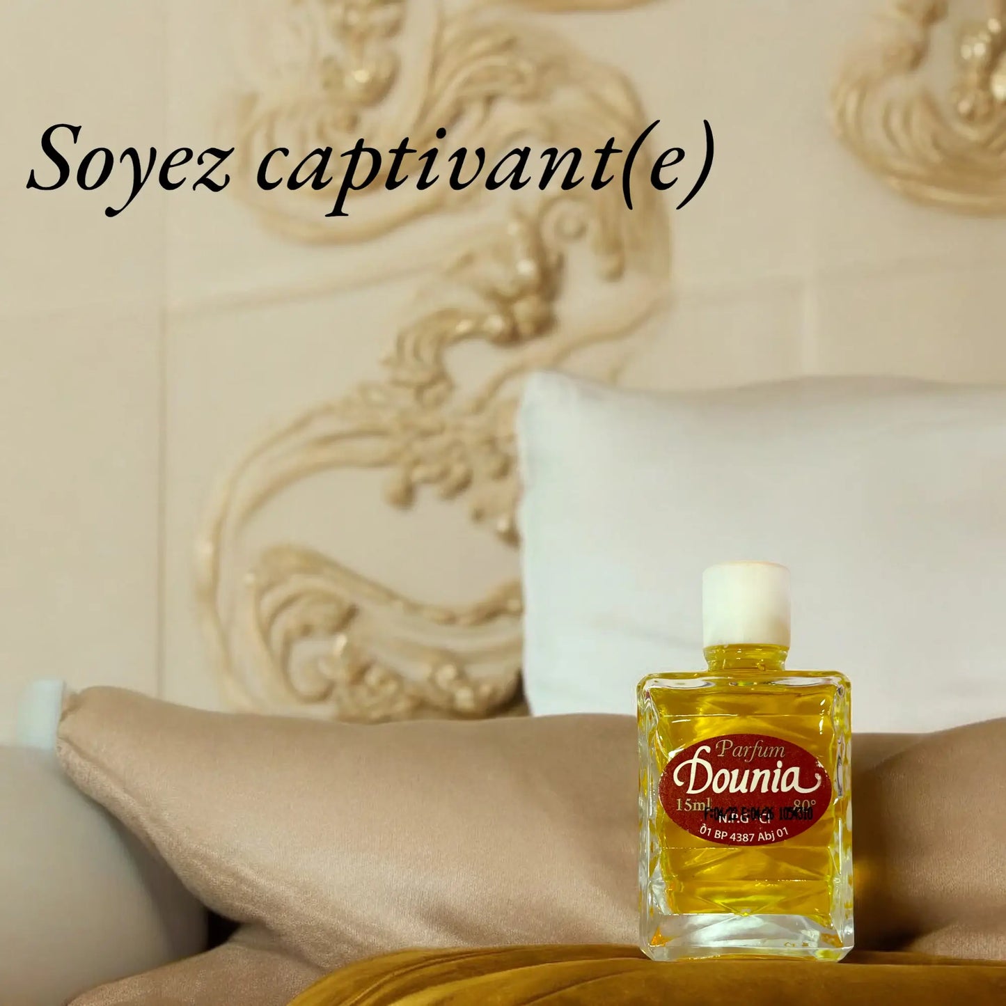 Une bouteille du parfum Dounia posée sur un luxueux sofa. Le slogan "Soyez captivante" est écrit sur la photo.