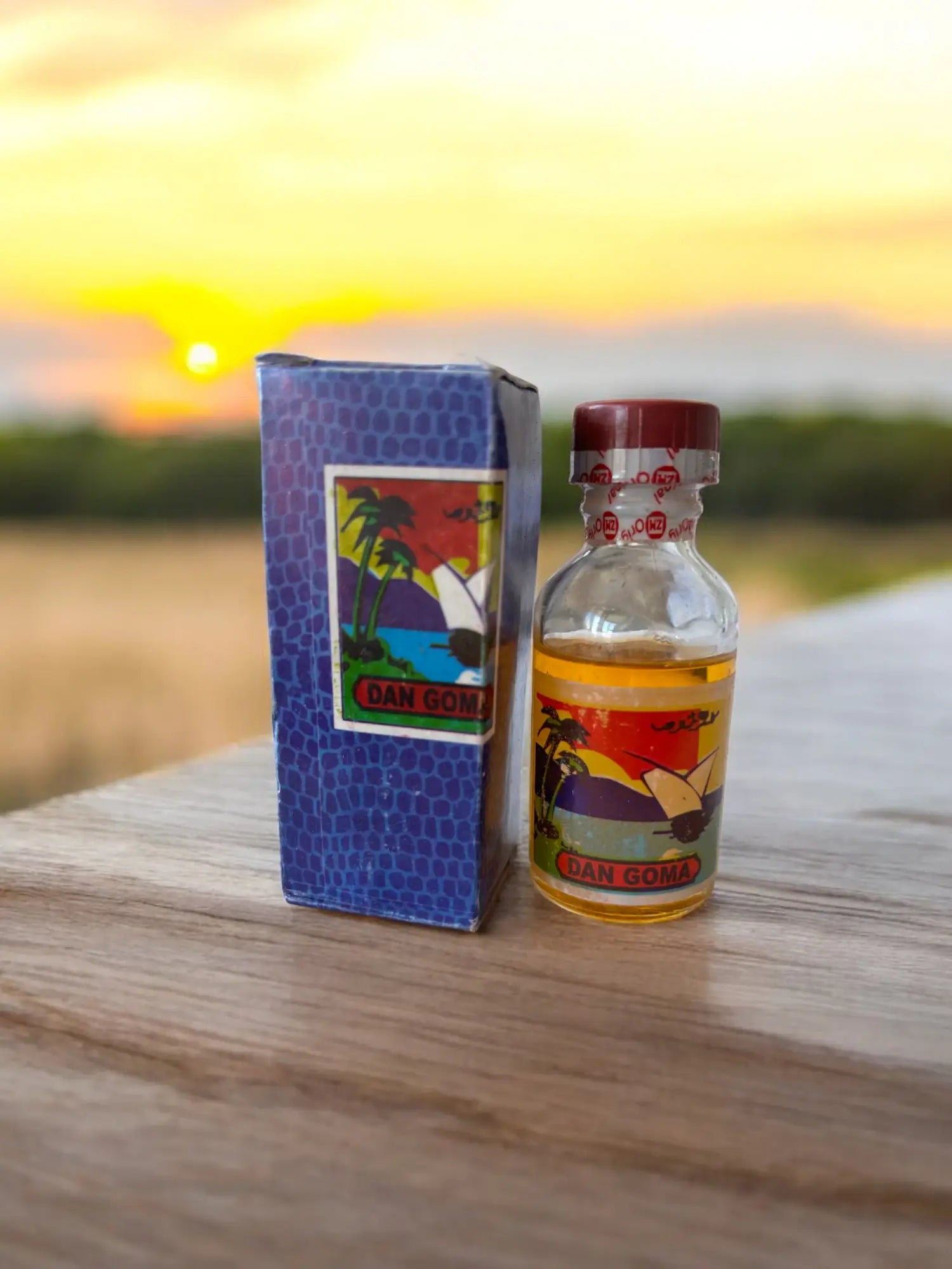 Une bouteille du parfum sans alcool Dan Goma posée sur une table devant un couché de soleil.