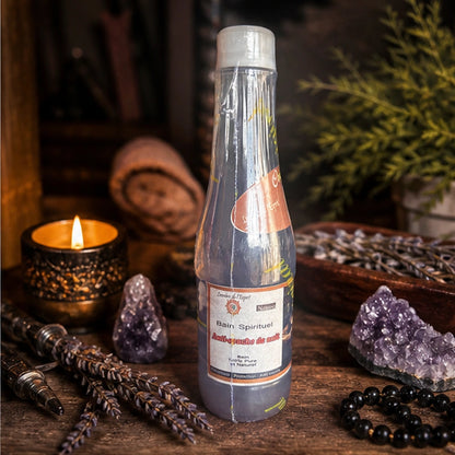 Flacon de bain spirituel anti couche de nuit présenté dans une ambiance rituelle nocturne avec bougie, lavande et pierres protectrices