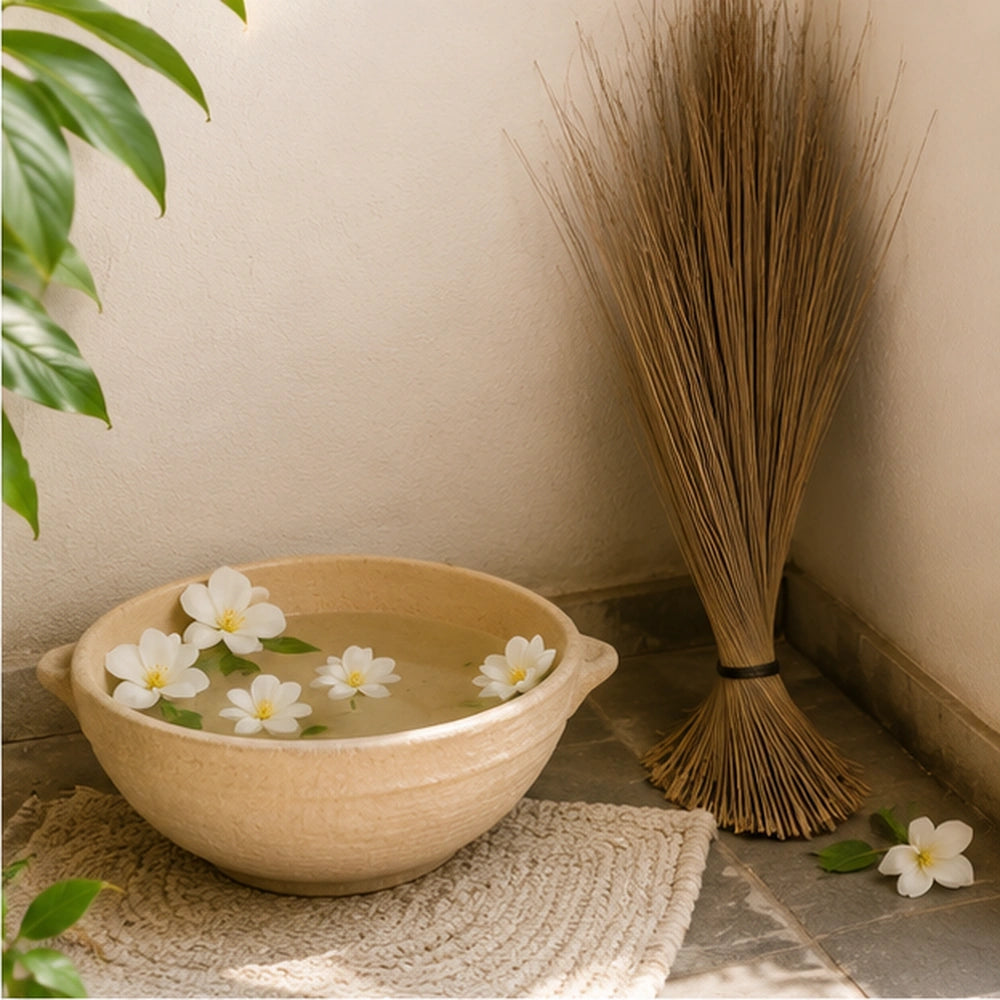 Balai traditionnel africain près d’un bol d’eau rituelle fleuri, pour évoquer purification et protection du foyer