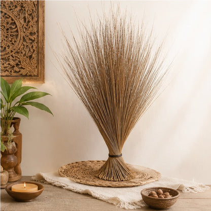 Balai africain de protection posé dans une mise en scène naturelle avec bougie, plantes et matières artisanales