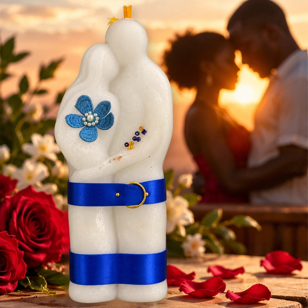 Bougie spirituelle Couple sculptée en deux silhouettes enlacées, ornée de rubans bleus, devant un couple au coucher du soleil.