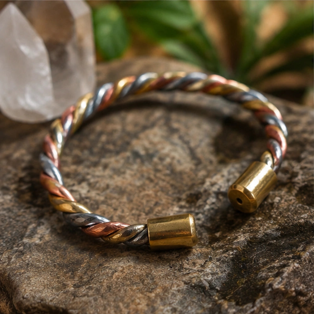 Gros plan sur le bracelet torsadé en cuivre, argent et laiton posé sur une pierre avec cristal naturel.