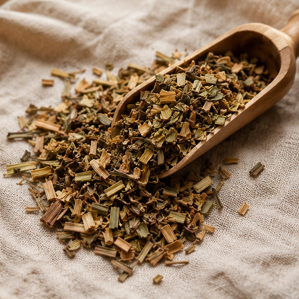 Feuilles de citronnelle séchées hachées dans une pelle en bois, présentées sur tissu naturel en décor bien-être.