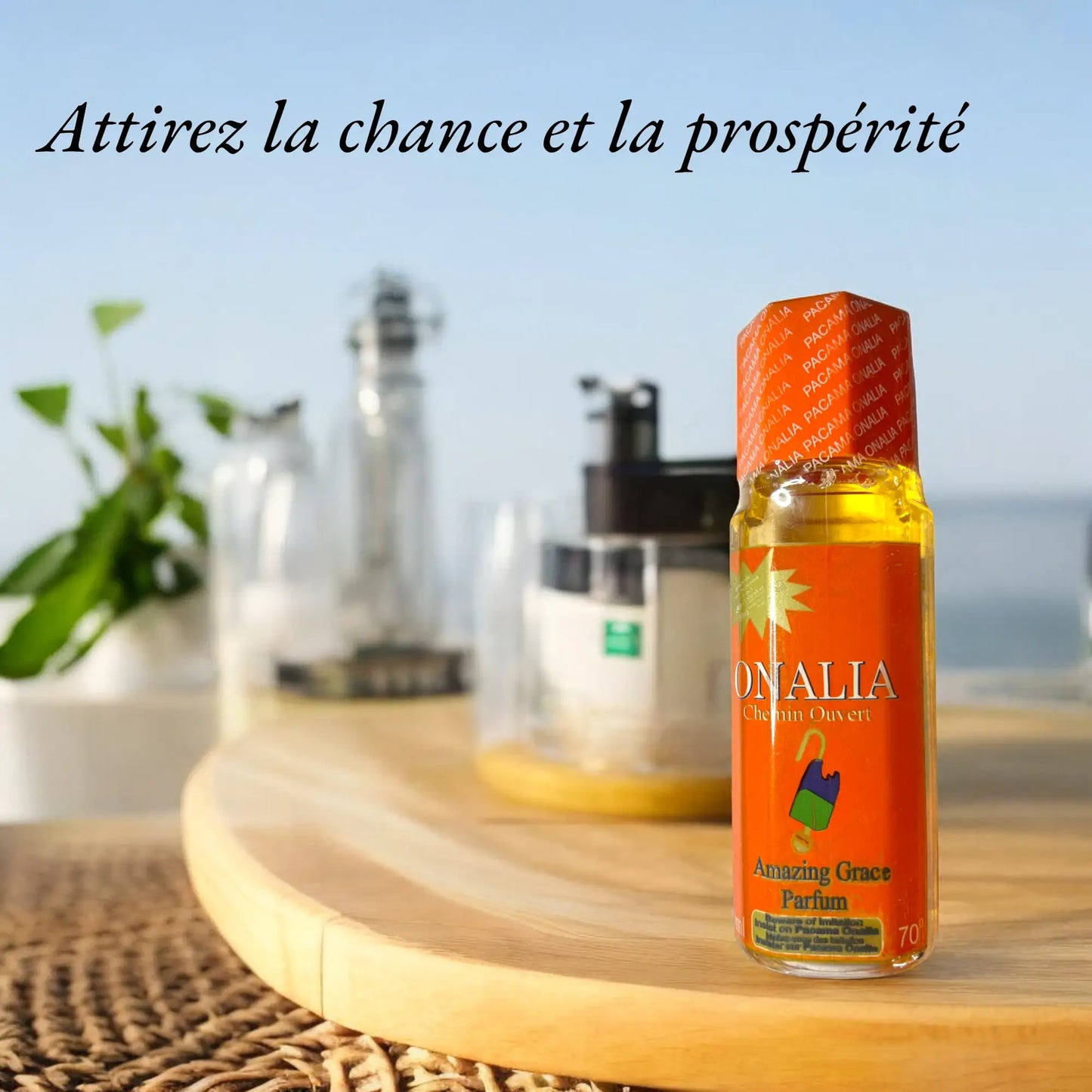 Une bouteille du parfum Onalia posée sur une table en bois avec la mer en arrière plan. Le slogan "Attirez la chance et la prospérité" est écrit sur la photo.