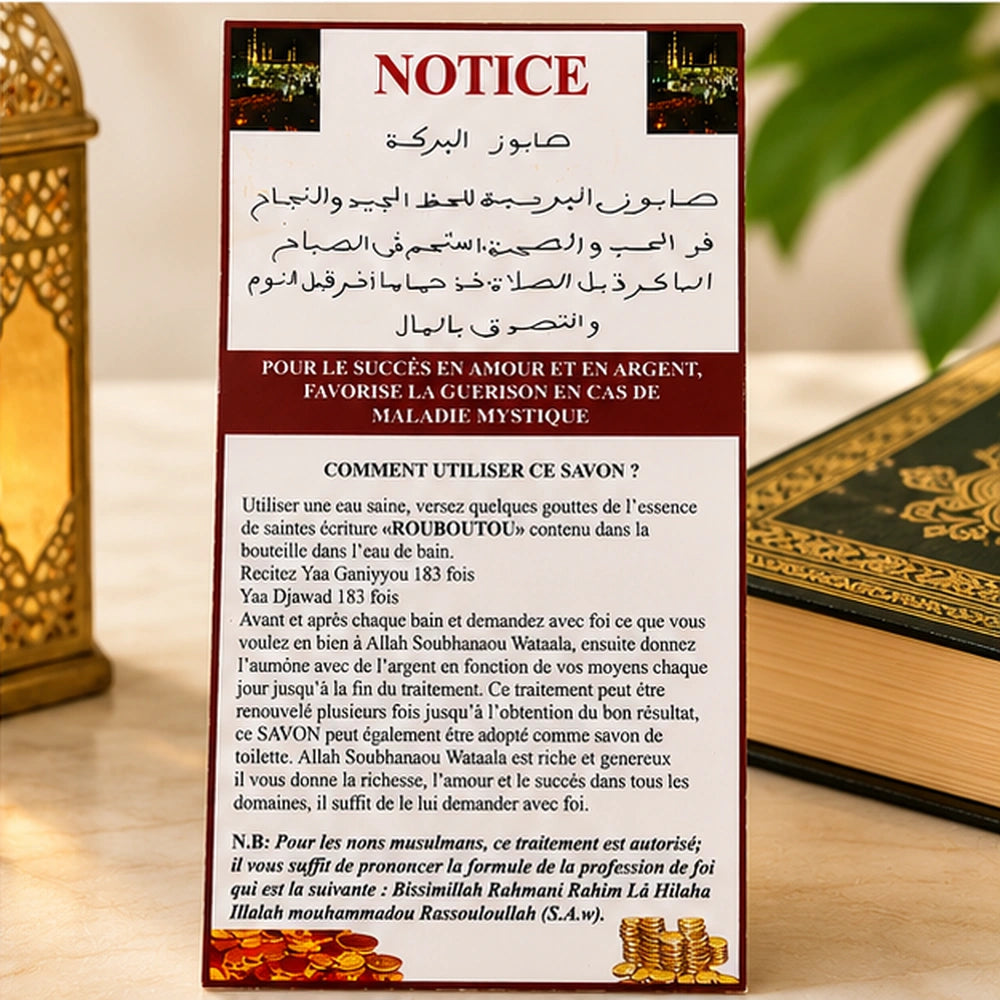 Notice du Savon Al Baraka mise en scène près d’un livre, détaillant le rituel avec l’essence Rouboutou.