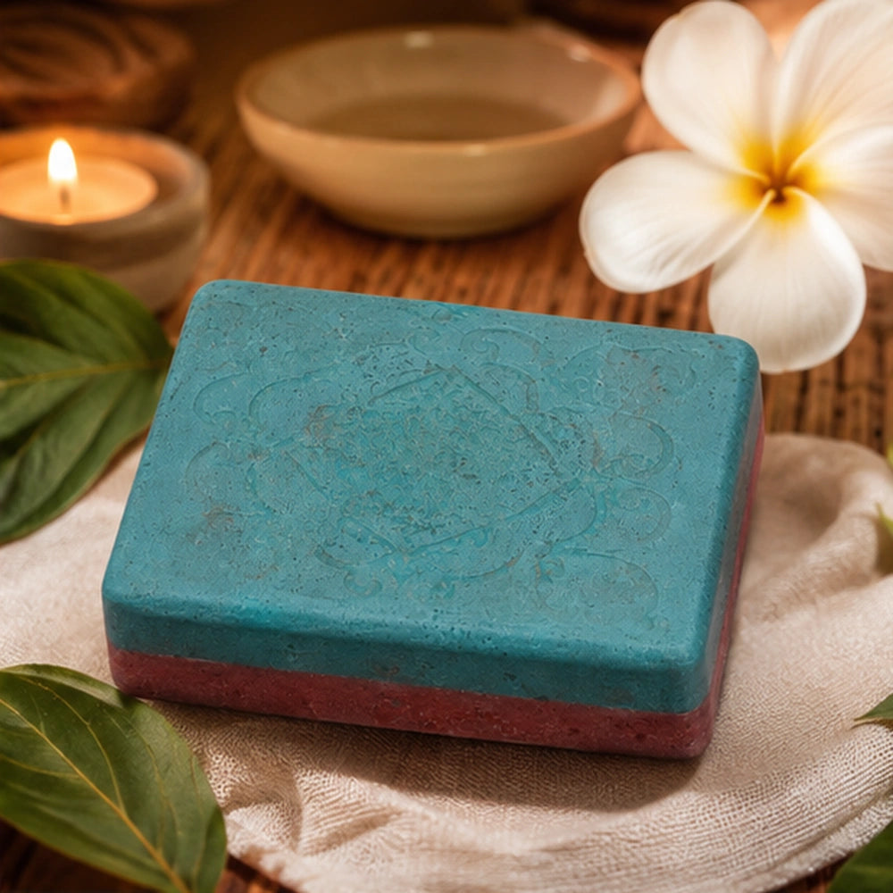 Savon Harmonie face bleu-vert posé dans un décor zen avec bougie et fleurs blanches pour un rituel d’apaisement émotionnel